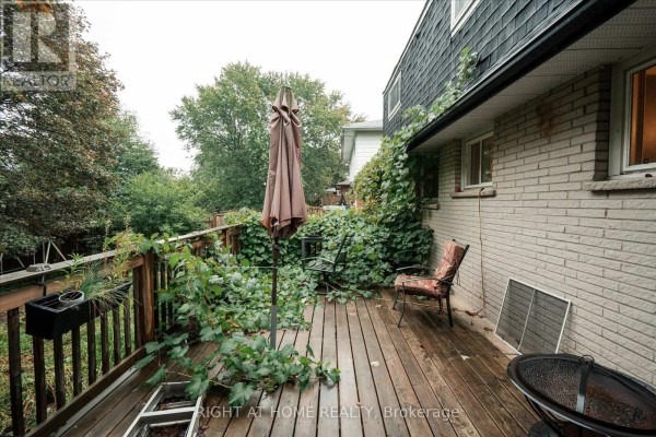 Wooden deck with umbrella, chairs, and overgrown ivy next to house - 701 Central Park Boulevard N Oshawa