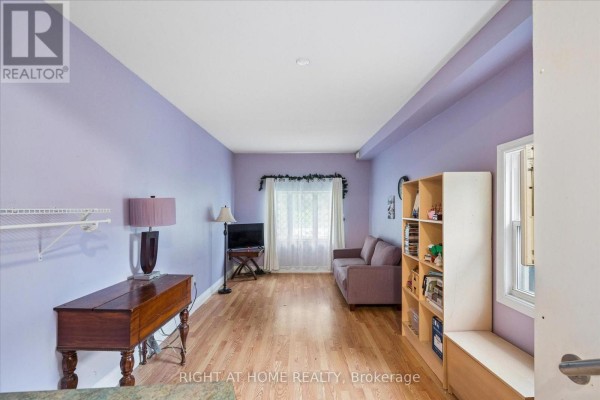 Living room with purple walls, hardwood floors, sofa, and shelf unit - 701 Central Park Boulevard N Oshawa