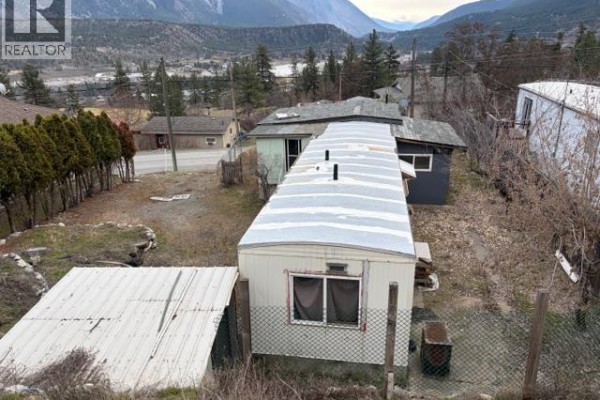 Aerial view of the property, showing a mobile home and fenced yard with nearby structures. - 701 Columbia Street, Lillooet