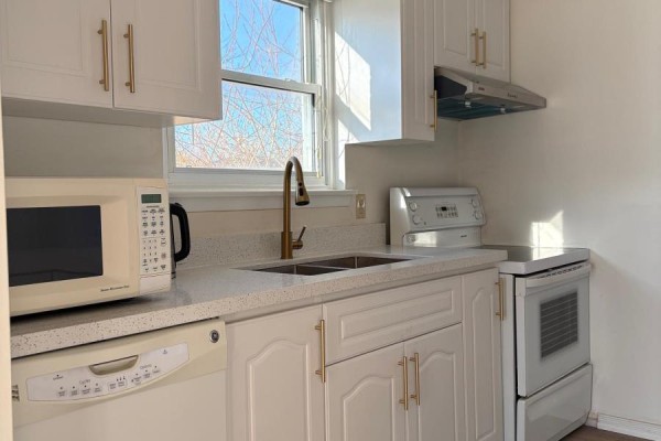 Close-up of white kitchen cabinets with gold hardware and a quartz countertop. - 701 Leeder Court, Newmarket