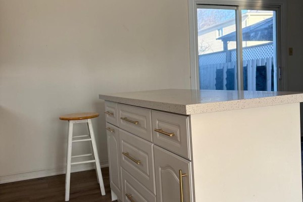Kitchen island with quartz countertop and a white stool in front of it. - 701 Leeder Court, Newmarket