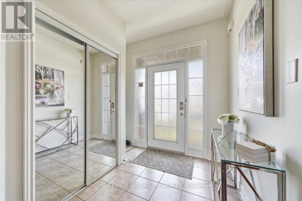 Interior entryway with beige tile floors, mirrored closet doors, and a glass-paneled front door. - 7010 Gooderham Estate Boulevard, Mississauga