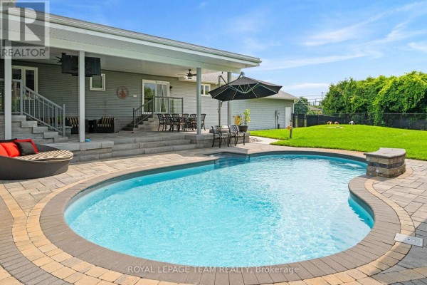 View of the backyard pool, patio, covered seating area, and grass lawn. - 7019 Cosgrove Avenue, Ottawa
