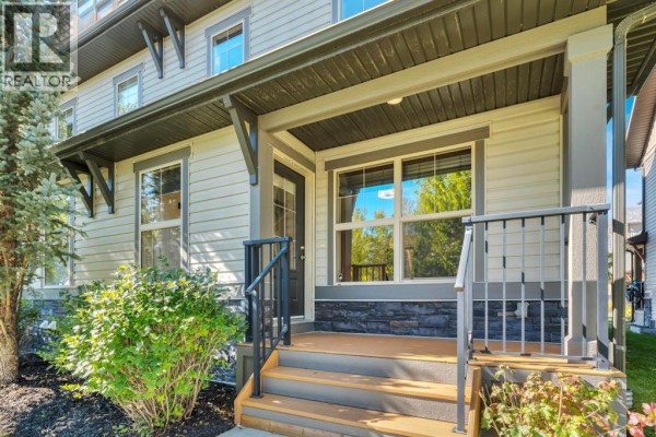 Close-up of the townhouse entrance with a covered porch and stone accent siding. - 702, 50 Belgian Lane, Cochrane