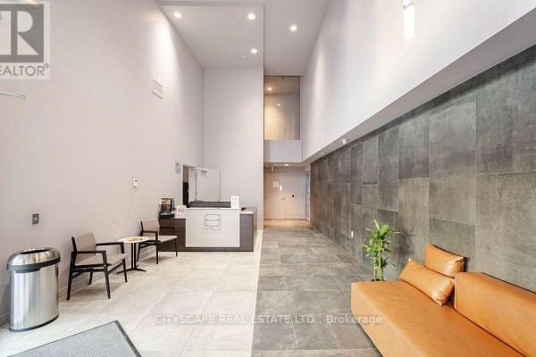 Empty bedroom with hardwood floors and a large window overlooking city buildings. - 702 - 2433 Dufferin Street, Toronto