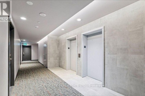 Empty room with hardwood floors and cream-colored walls, reflecting in a mirrored closet door. - 702 - 2433 Dufferin Street, Toronto