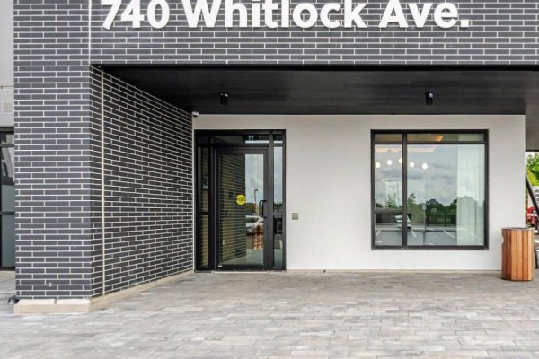 Lobby seating area with a large sectional sofa, modern chairs, coffee tables, and large windows. - 702 - 740 Whitlock Avenue, Milton