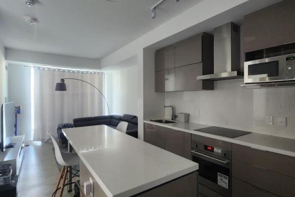 Open concept living area and kitchen with island, modern grey cabinets, and stainless steel appliances. - 702 - 8 Rouge Valley Drive W, Markham