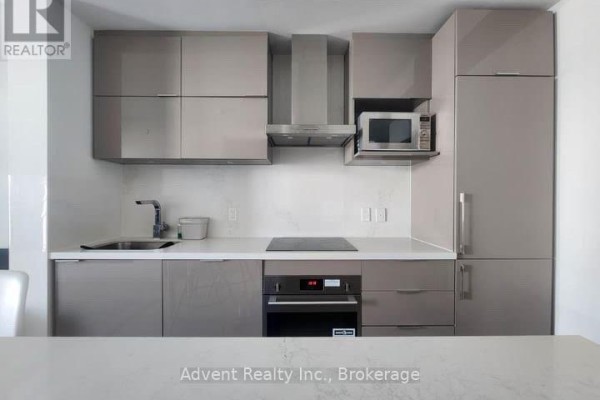 Close-up of a modern kitchen with grey cabinets, stainless steel appliances, and induction stovetop. - 702 - 8 Rouge Valley Drive W, Markham