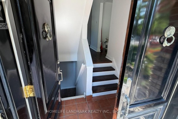 Looking through open black double doors into a hallway with a staircase and hardwood floors. - 702 Sheppard Ave E Avenue E, Toronto