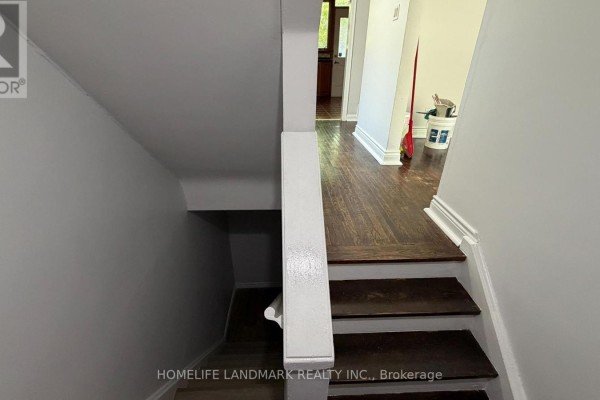 View down a staircase with dark wood treads and white risers, leading to a hallway. - 702 Sheppard Ave E Avenue E, Toronto