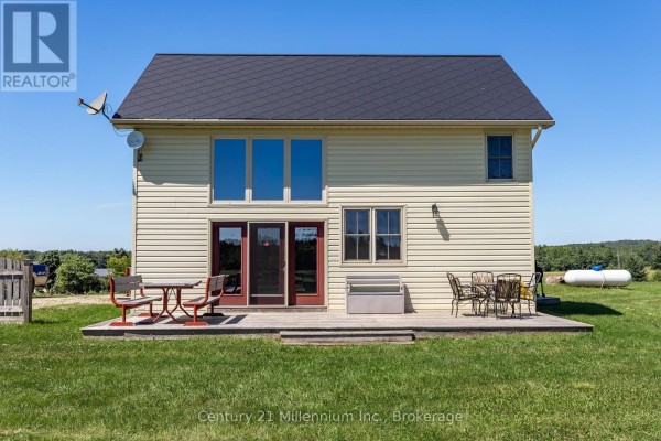 Back deck of the farmhouse with patio furniture and views of the surrounding fields. - 702174 Sideroad 5, Chatsworth