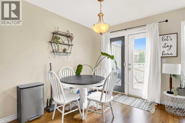 Dining area with a round table, four chairs, and patio doors leading outside. - 7025 112 Street, Grande Prairie