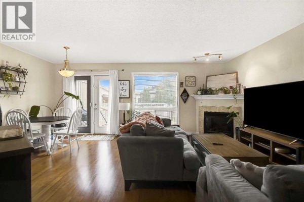 Open-concept living and dining area with hardwood floors and a fireplace. - 7025 112 Street, Grande Prairie