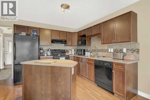 Kitchen with dark wood cabinets, granite countertops, and a center island. - 7025 112 Street, Grande Prairie