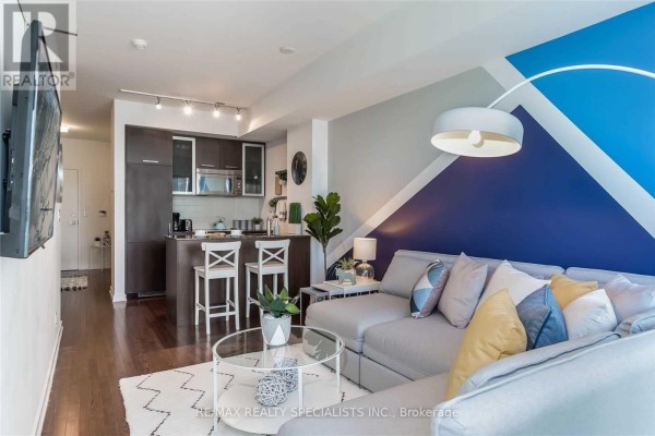 A tall faux plant sits next to a mirrored closet door with stacked laundry machines. - 703 - 12 York Street, Toronto
