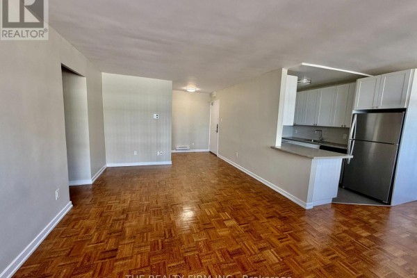 Living room with parquet flooring, light gray walls, and a breakfast bar connecting to the kitchen. - 703 - 1209 Richmond Street, London East