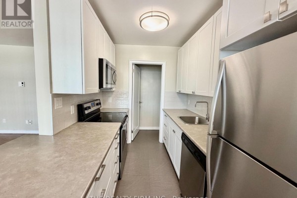 Kitchen with white cabinets, stainless steel appliances, gray countertops, and a white subway tile backsplash. - 703 - 1209 Richmond Street, London East