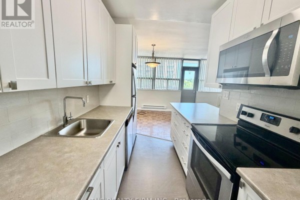 Kitchen with white cabinets, stainless steel appliances, and a view of the dining area and window. - 703 - 1209 Richmond Street, London East