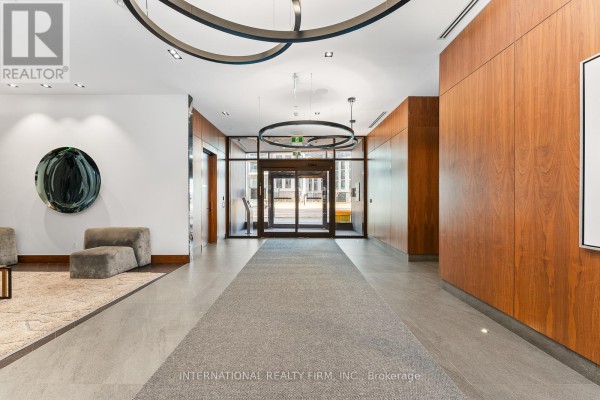 Building lobby with a long grey carpet runner, wood-paneled walls, and modern circular light fixtures. - 703 - 7895 Jane Street, Vaughan