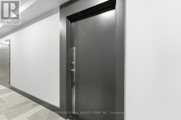 Close-up of a dark grey apartment door with a silver handle and a white hallway. - 703 - 7895 Jane Street, Vaughan