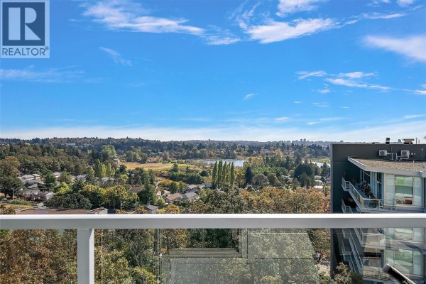 View from balcony of a landscape with trees, buildings, and a lake. - 703 4011 Rainbow Hill Lane, Saanich