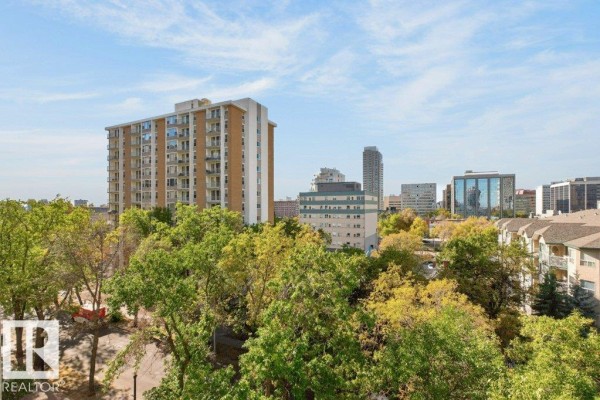 View of Edmonton skyline and apartment building with trees. - #703 9921 104 St Nw, Edmonton
