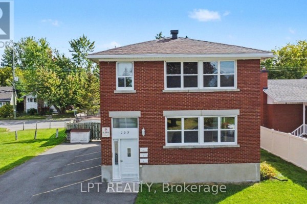 Three-quarter front view of a red brick duplex with a driveway and lawn. - 703 Morgan Street, Ottawa