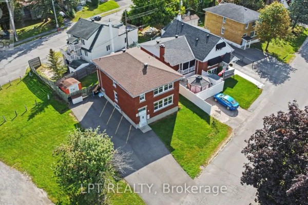 Aerial view of a red brick duplex with surrounding houses, driveway, and lawn. - 703 Morgan Street, Ottawa