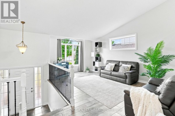 Living area featuring a leather sofa, large window, and decorative plants. - 7032 Kelly Drive, Niagara Falls
