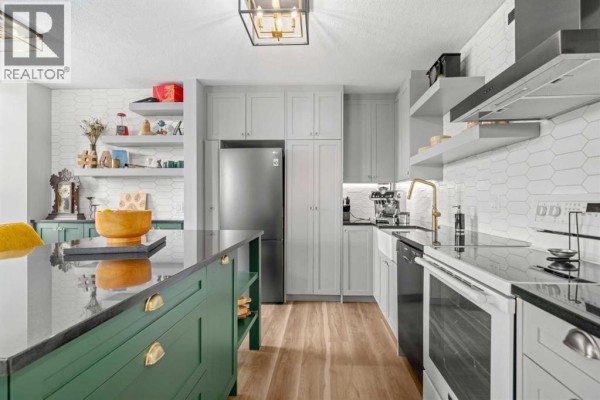 Kitchen with light grey cabinets, a stainless steel refrigerator, and dark granite countertops. - 704, 1202 13 Avenue Sw, Calgary