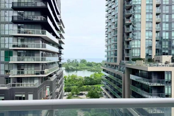 View of water and trees between two tall apartment buildings from a balcony. - 704 - 56 Annie Craig Drive, Toronto