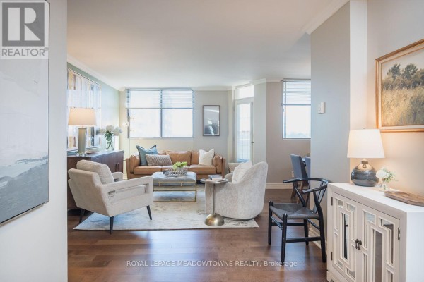 Living room with leather sofa, armchairs, rug, and view of the dining area. - 704 - 81 Millside Drive, Milton