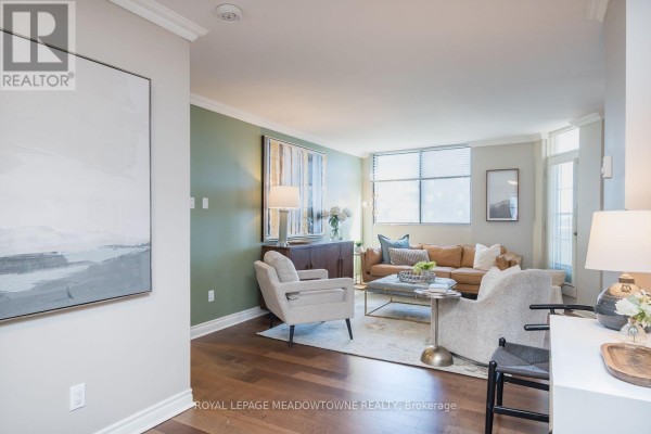 Living area with green accent wall, seating, and view of the kitchen area. - 704 - 81 Millside Drive, Milton