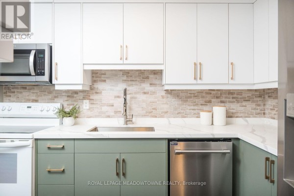 Kitchen with white and green cabinets, stainless steel appliances, and marble countertops. - 704 - 81 Millside Drive, Milton