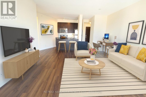 Living room with a sofa, armchair, coffee table, desk, and kitchen in the background. - 704 - 85 The Donway W, Toronto