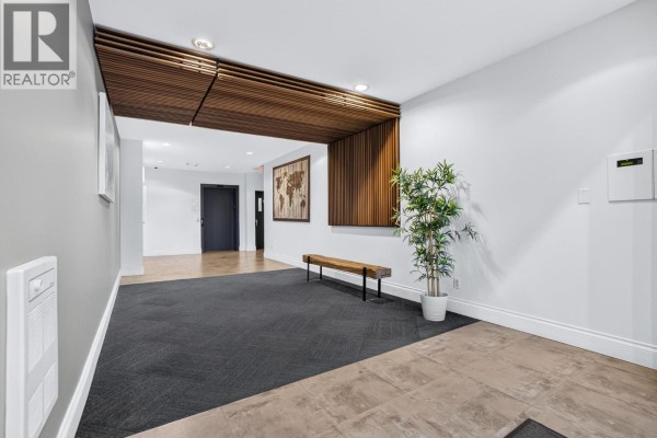 Building lobby with dark carpet, wood accents, and bench. - 704 415 E Columbia Street, New Westminster