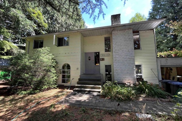 View of a large backyard with mature trees, a wooden fence, and a grassy lawn. - 7048 140a Street, Surrey