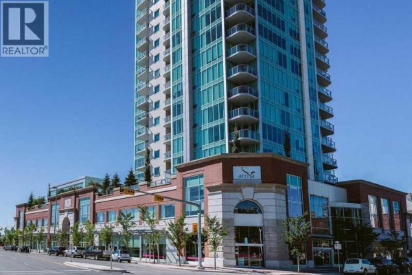 Living room with sectional sofa, coffee table, and large windows overlooking city. - 705, 433 11 Avenue Se, Calgary