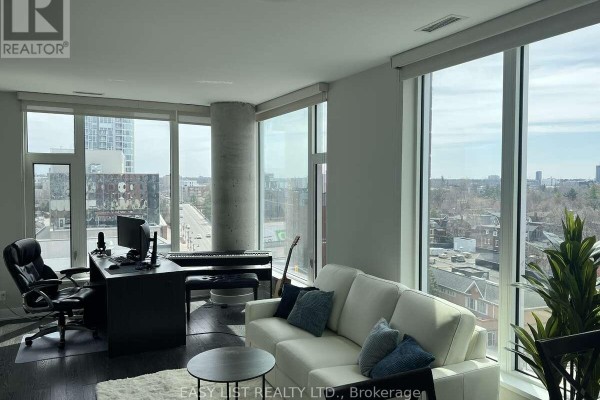 Living room with sofa, desk, computer, piano, and large windows overlooking the city. - 705 - 118 Holmwood Avenue, Ottawa