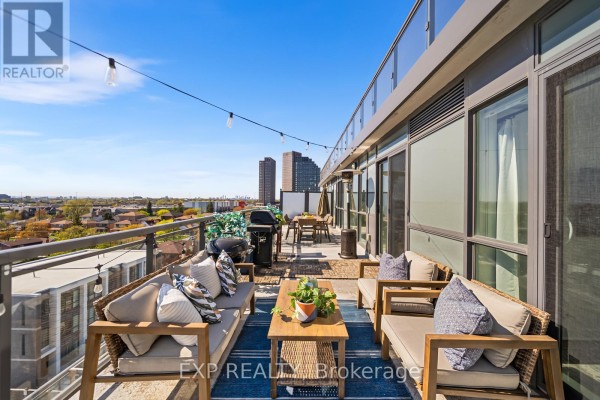 Living room with a white sofa, entertainment unit, and large window. - 705 - 16 Mcadam Avenue, Toronto