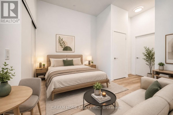 A bedroom with a king-size bed, bedside tables, a sofa, and a small dining table. - 705 - 285 Dufferin Street, Toronto