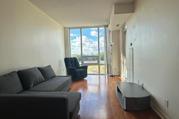 Living room featuring a sectional sofa, recliner, entertainment unit, and large window with a view. - 705 - 3525 Kariya Drive, Mississauga
