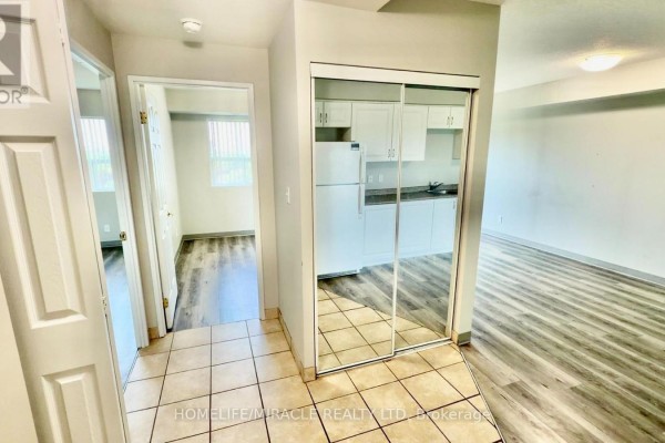 Interior hallway with tile floor, showing entrance to a kitchen with mirrored closet doors. - 705 - 593 Strasburg Road, Kitchener