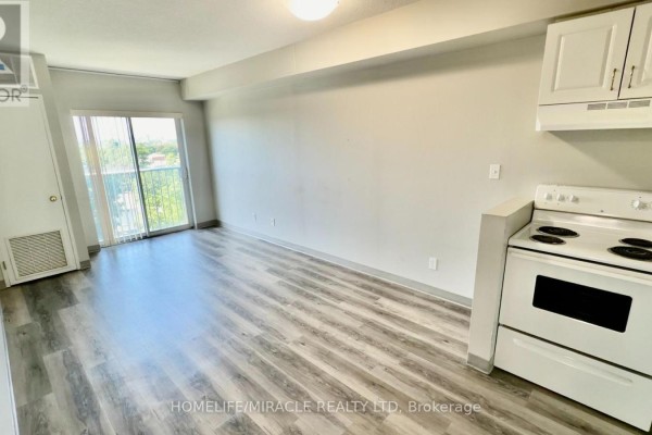 View of a living area with grey wood-look flooring, sliding glass doors, and a white stove. - 705 - 593 Strasburg Road, Kitchener