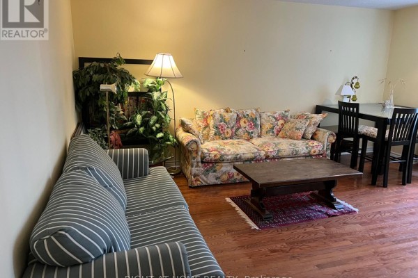 Living room with striped sofa, floral sofa, wooden coffee table, and dining table. - 705 - 71 Simcoe Street, Toronto