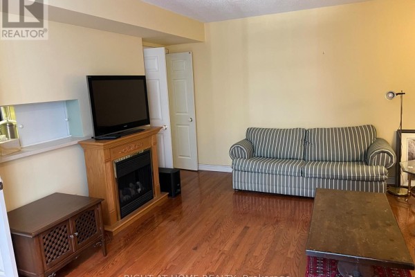 Living room with sofa, electric fireplace, media console, and doorway to another room. - 705 - 71 Simcoe Street, Toronto