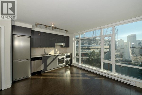 Empty apartment interior with dark hardwood floors, white walls, and several doorways. - 705 161 W Georgia Street, Vancouver