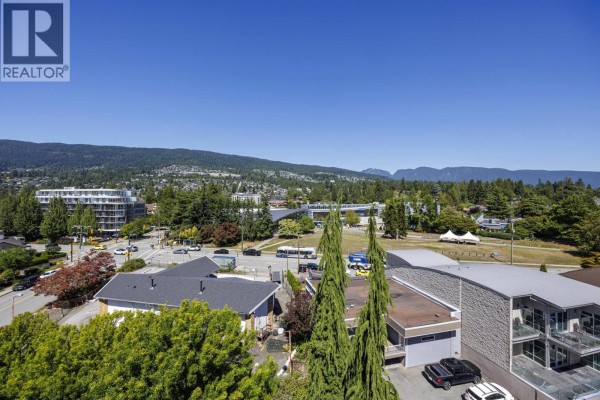 View of the apartment building and surrounding cityscape with mountains in the background. - 705 2187 Bellevue Avenue, West Vancouver