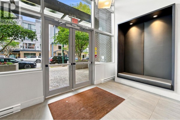 Building lobby with glass doors, tiled floor, and a recessed gray bench nook. - 705 538 W 7th Avenue, Vancouver